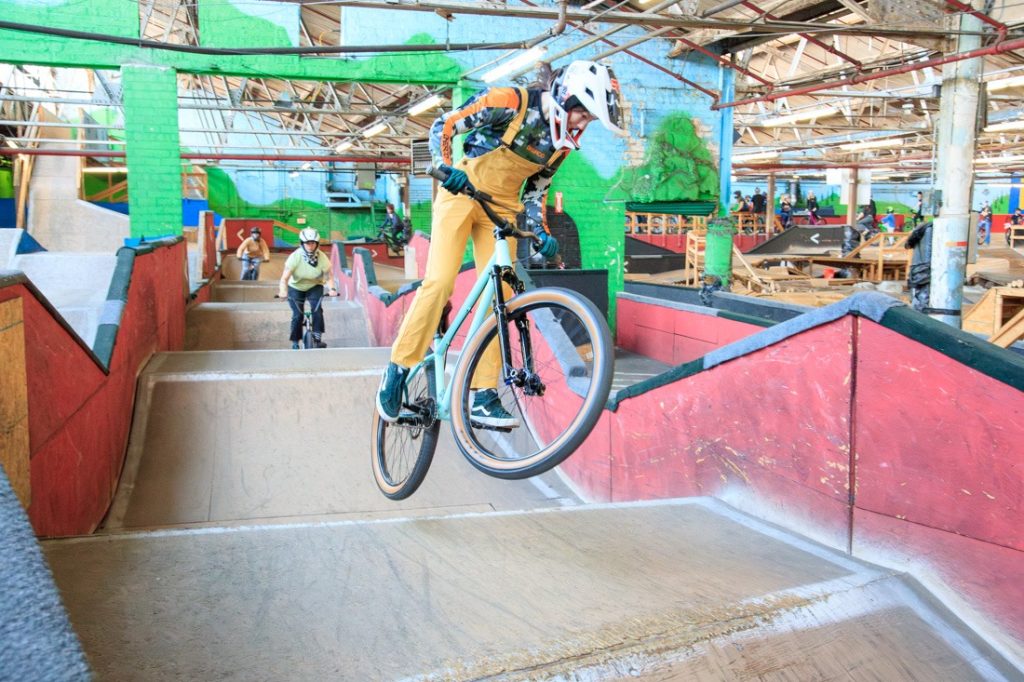 A rider on a wooden jump line inside Ray's Indoor Bike Park